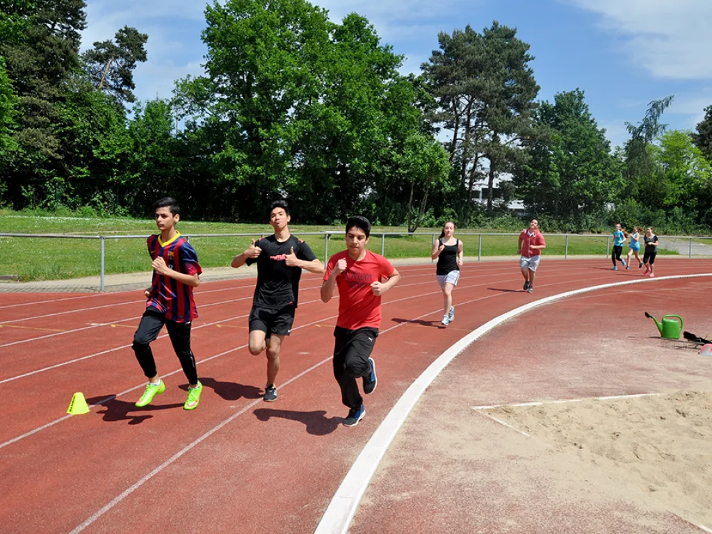 Drei Läufer sprinten in der Kurve.